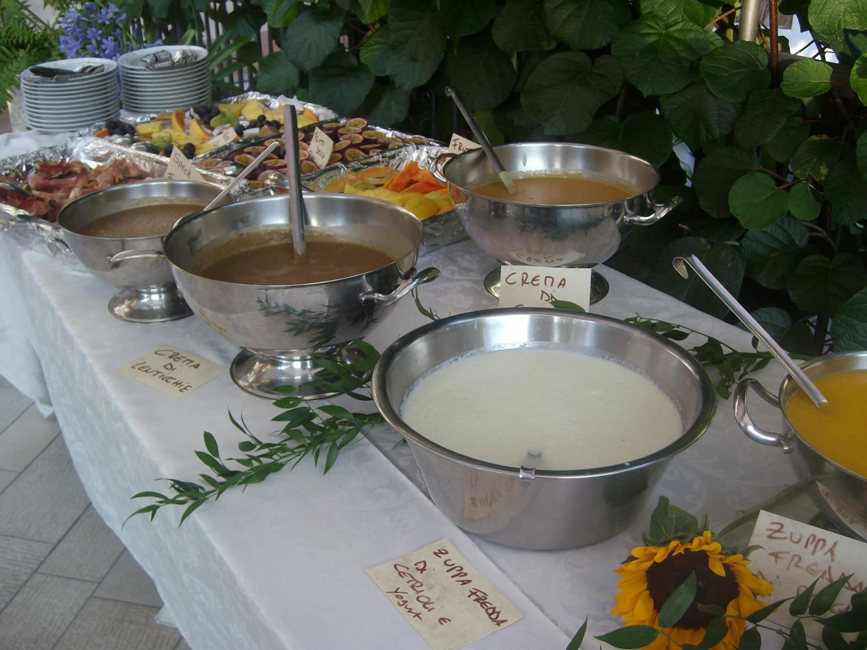 Een buffet met diverse gerechten en dranken, waaronder pannenkoeken, yoghurt en een grote kom soep.
