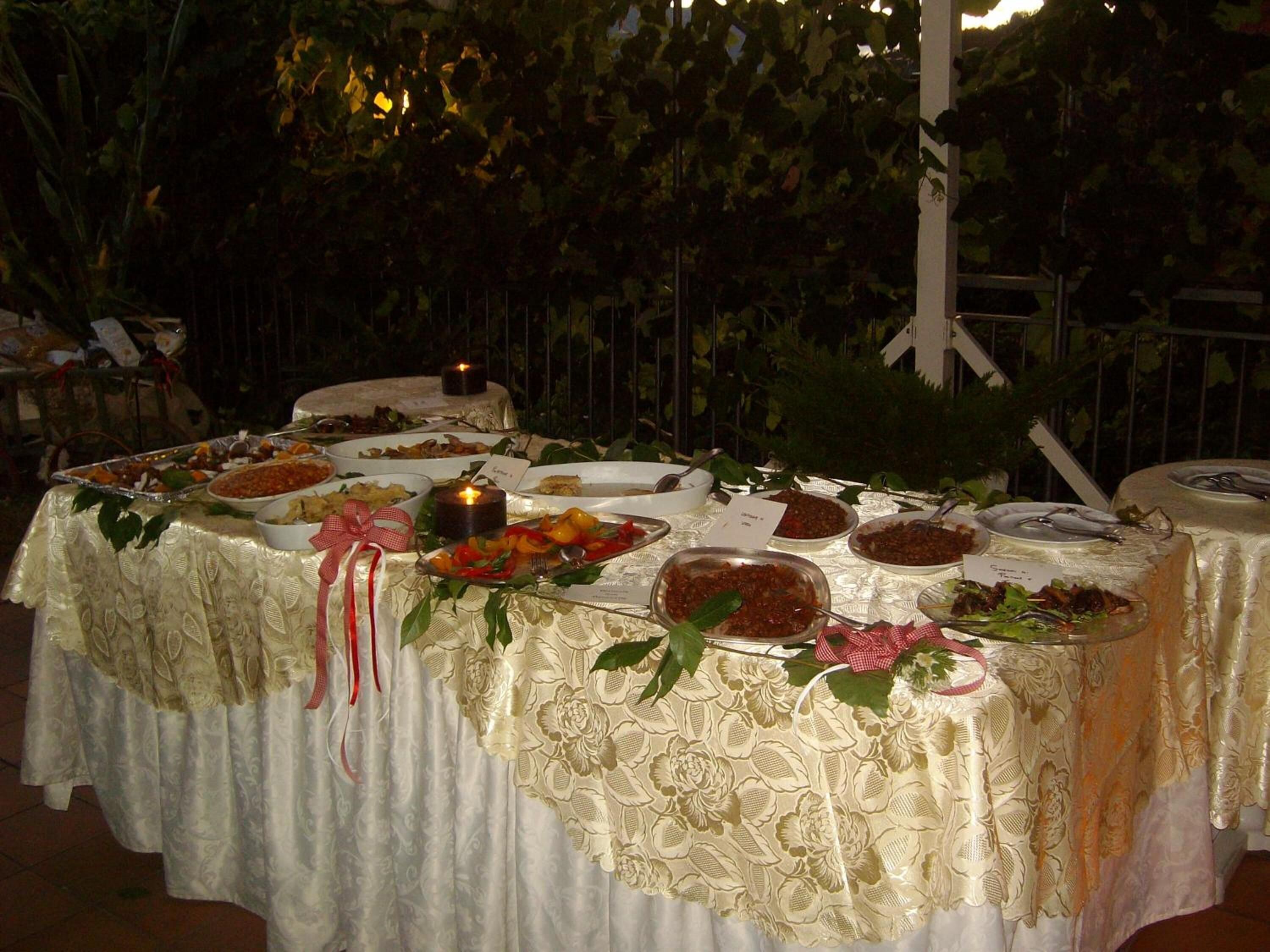 An outdoor dining table set with various dishes, a candle, and decorative ribbons.