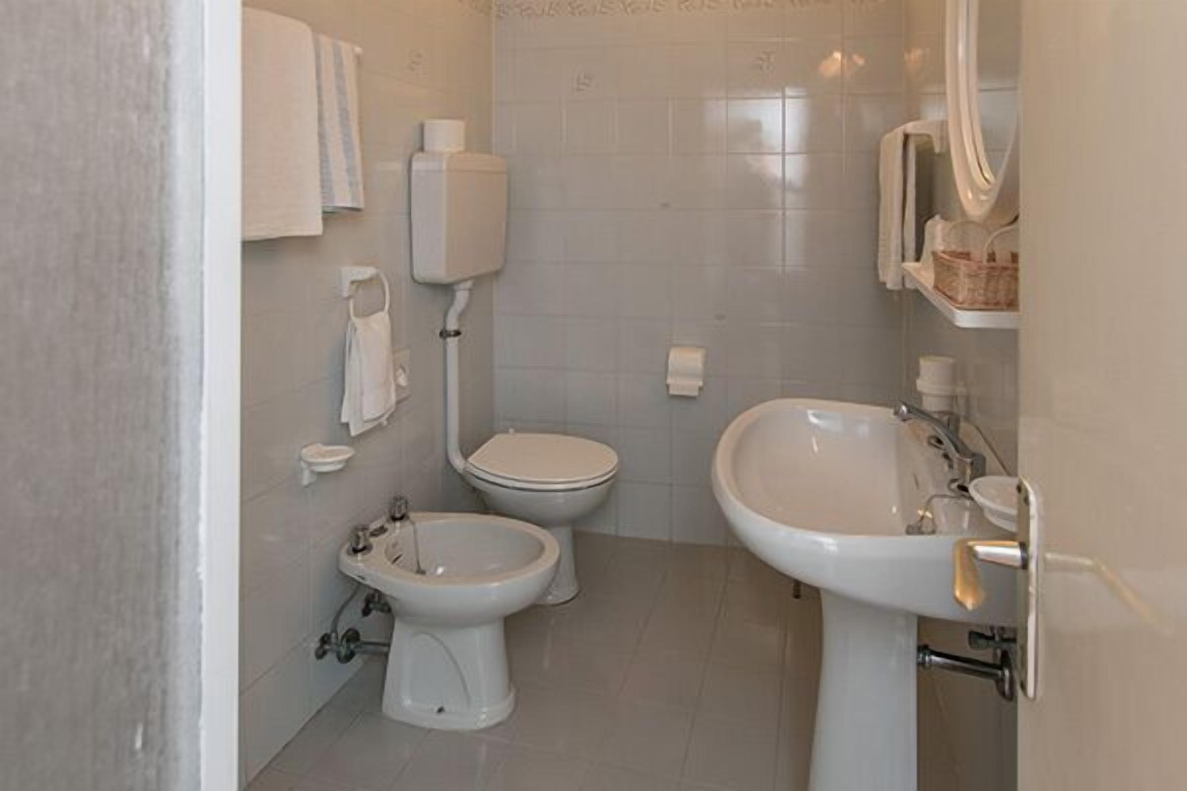 A small, clean bathroom with a toilet, bidet, and sink.