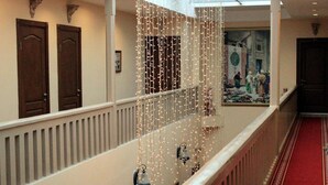 En hotellkorridor med en röd matta, trädörrar och en dekorativ ljusinstallation.