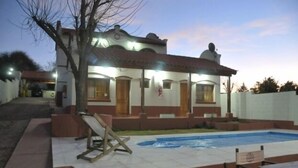 Una casa de dos pisos con piscina, un patio cubierto y una escalera que conduce al piso superior.