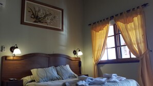Una cama bien hecha con almohadas, una lámpara de noche y un cuadro en la pared.