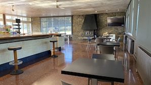 A modern bar area with a stone wall, a large TV, and a fireplace. - Hotel Solana del Ter (Ripoll)