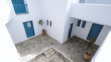 A courtyard with stone flooring, white walls, and blue doors and shutters.