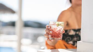 A person holding a cocktail glass with a tropical drink, near a poolside area.
