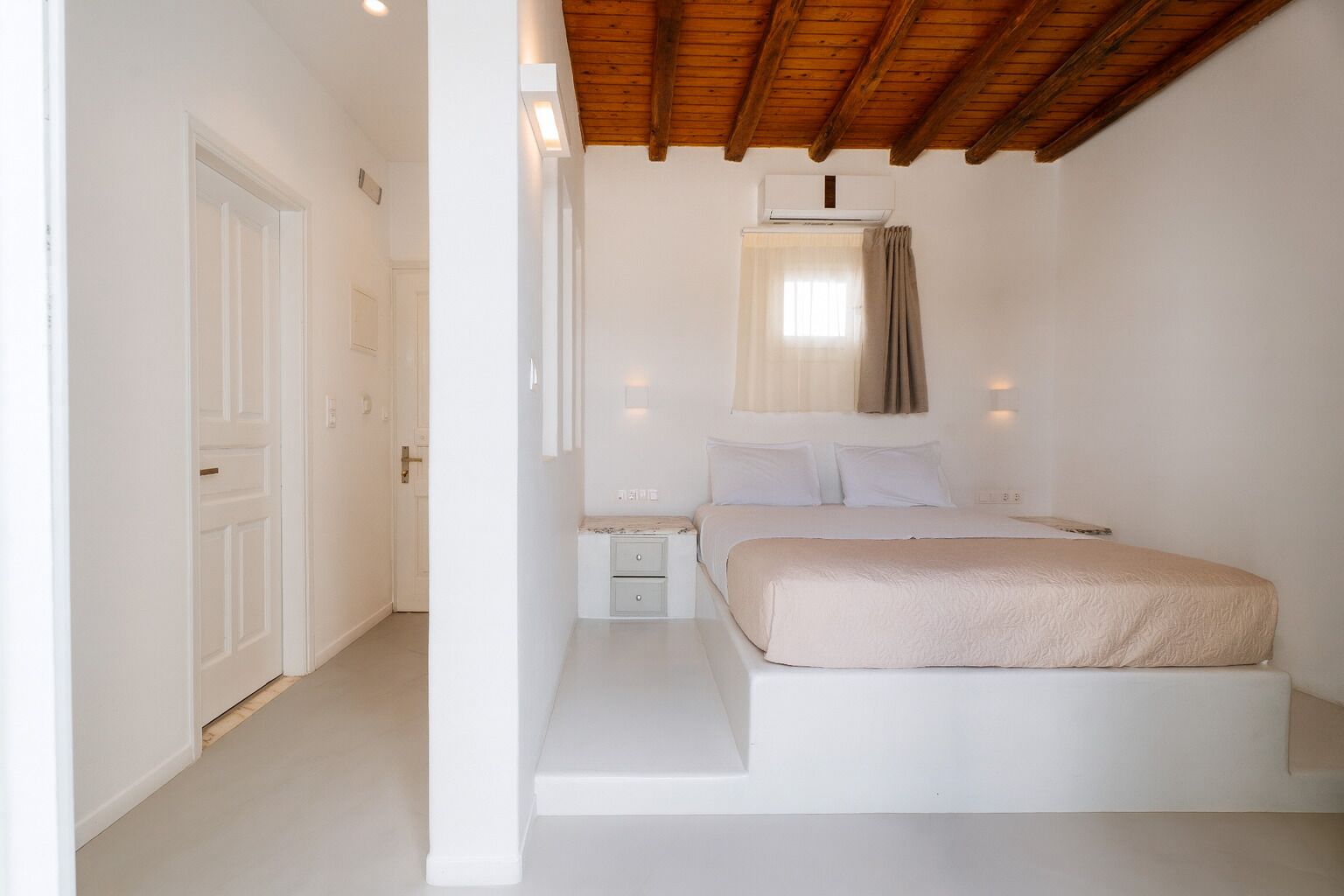 A bedroom with a bed, bedside tables, and a window with curtains.