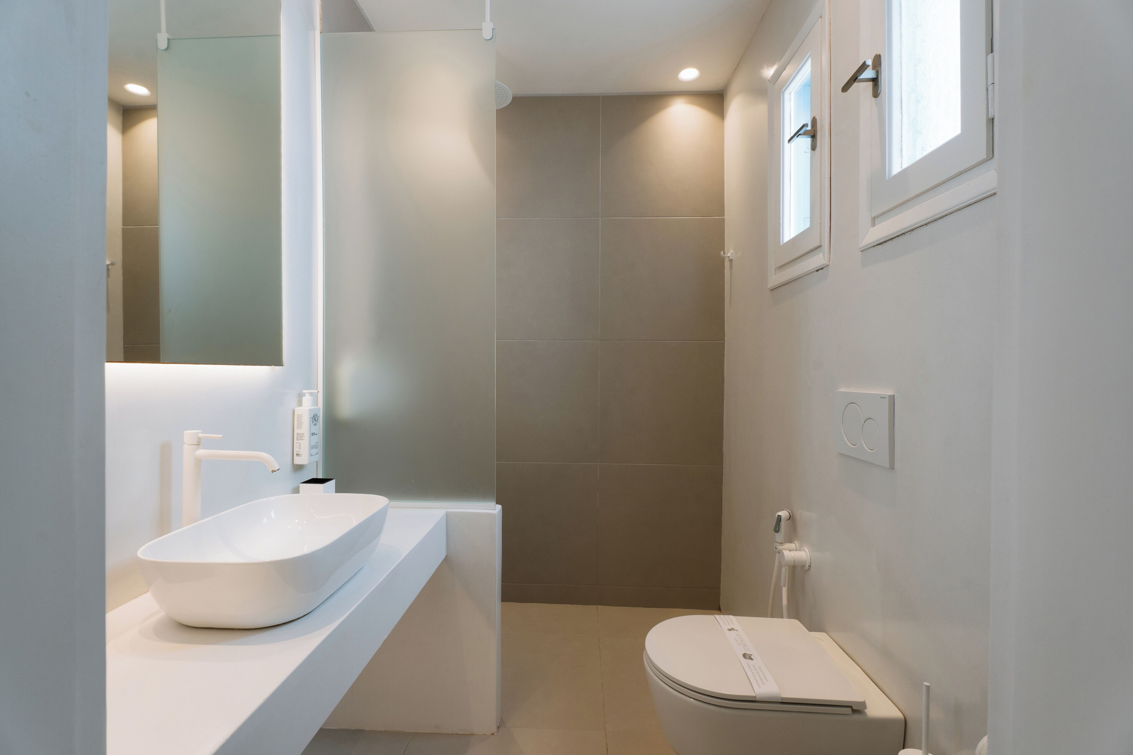 A modern bathroom with a white sink, a toilet, and a shower area.