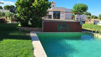 Una piscina al aire libre de temporada, sombrillas, tumbonas