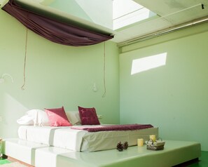 Une chambre avec un lit, une lucarne et une vue sur le ciel.