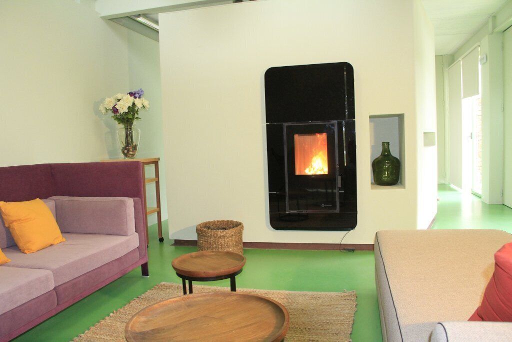 A living room with a fireplace, a sofa, a coffee table, and a vase with flowers.