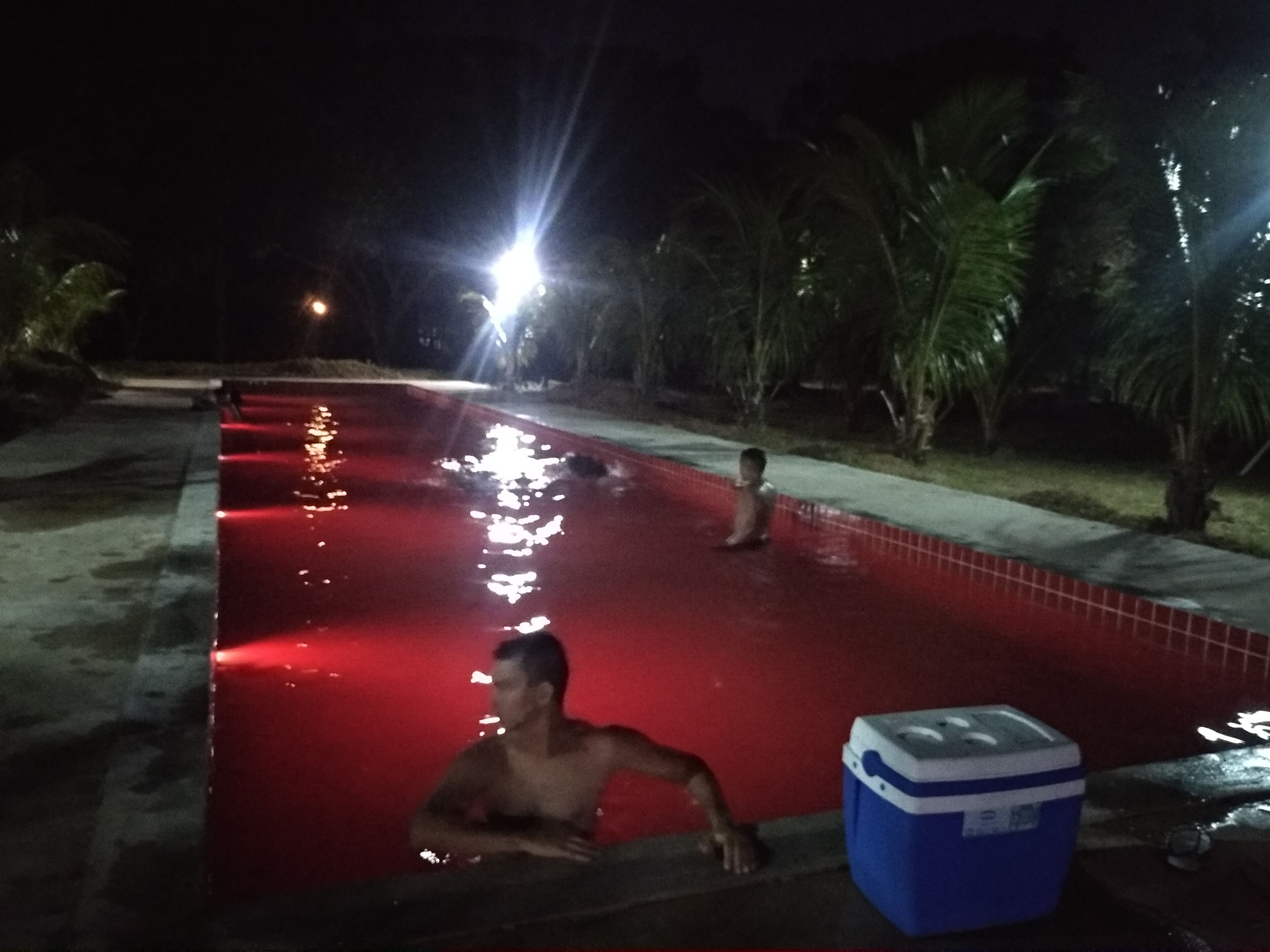 Una piscina por la noche, con reflejos en el agua.