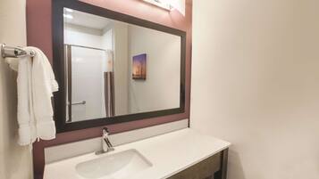A bathroom with a white sink, a large mirror, and a towel hanging on a rack.