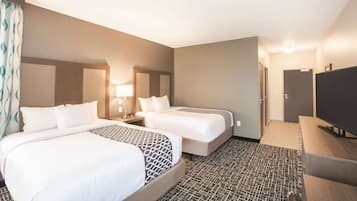 Une chambre d’hôtel avec deux lits, une télévision, un bureau et une moquette à motifs.