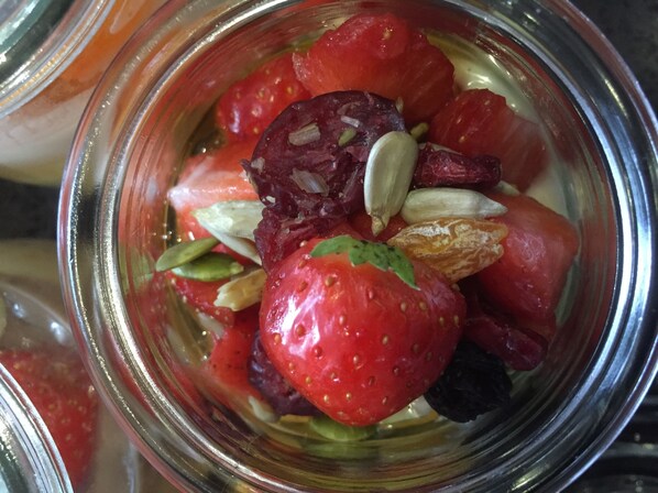 A glass jar filled with sliced tomatoes, a whole strawberry, and pumpkin seeds. - Westcourt Guest House (Fort William)