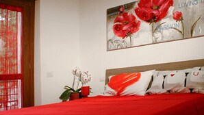 A bedroom with a red bedspread, a wooden headboard, and a wall-mounted painting of red flowers. - B&B SheLisa (Rome)