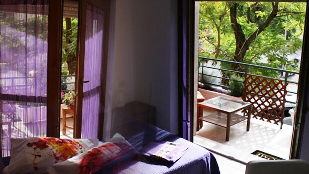 A room with a bed, a window with purple curtains, and a view of a balcony with a table and chairs. - B&B SheLisa (Rome)