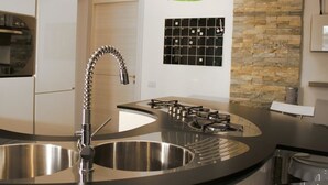 A modern kitchen with a curved island, stainless steel sink, and a gas stove. - B&B SheLisa (Rome)