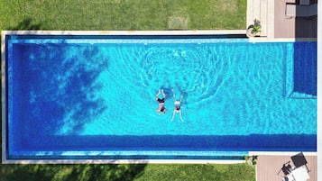Relax by the pool surrounded by lush greenery and a serene atmosphere.