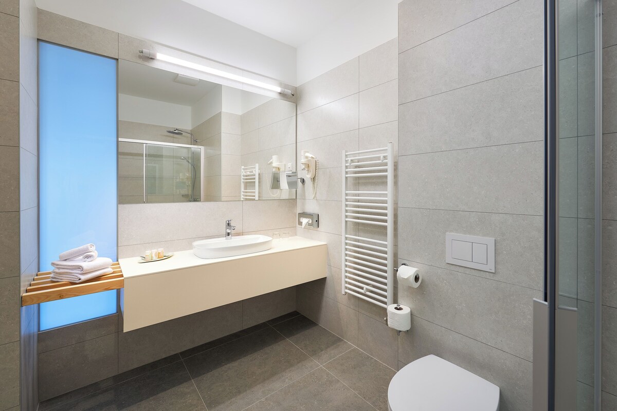 A modern bathroom with a sink, mirror, towel rack, and a glass shower enclosure.