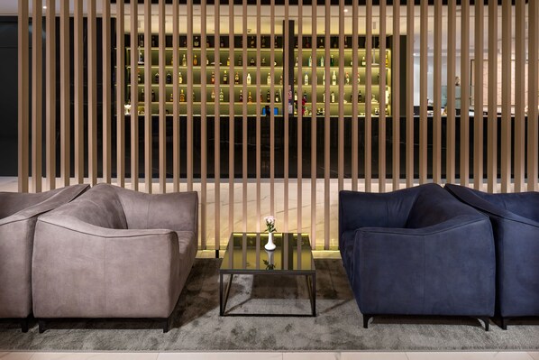 Un salon moderne avec deux canapés, une table basse en verre et un mur décoratif agrémenté d’étagères.
