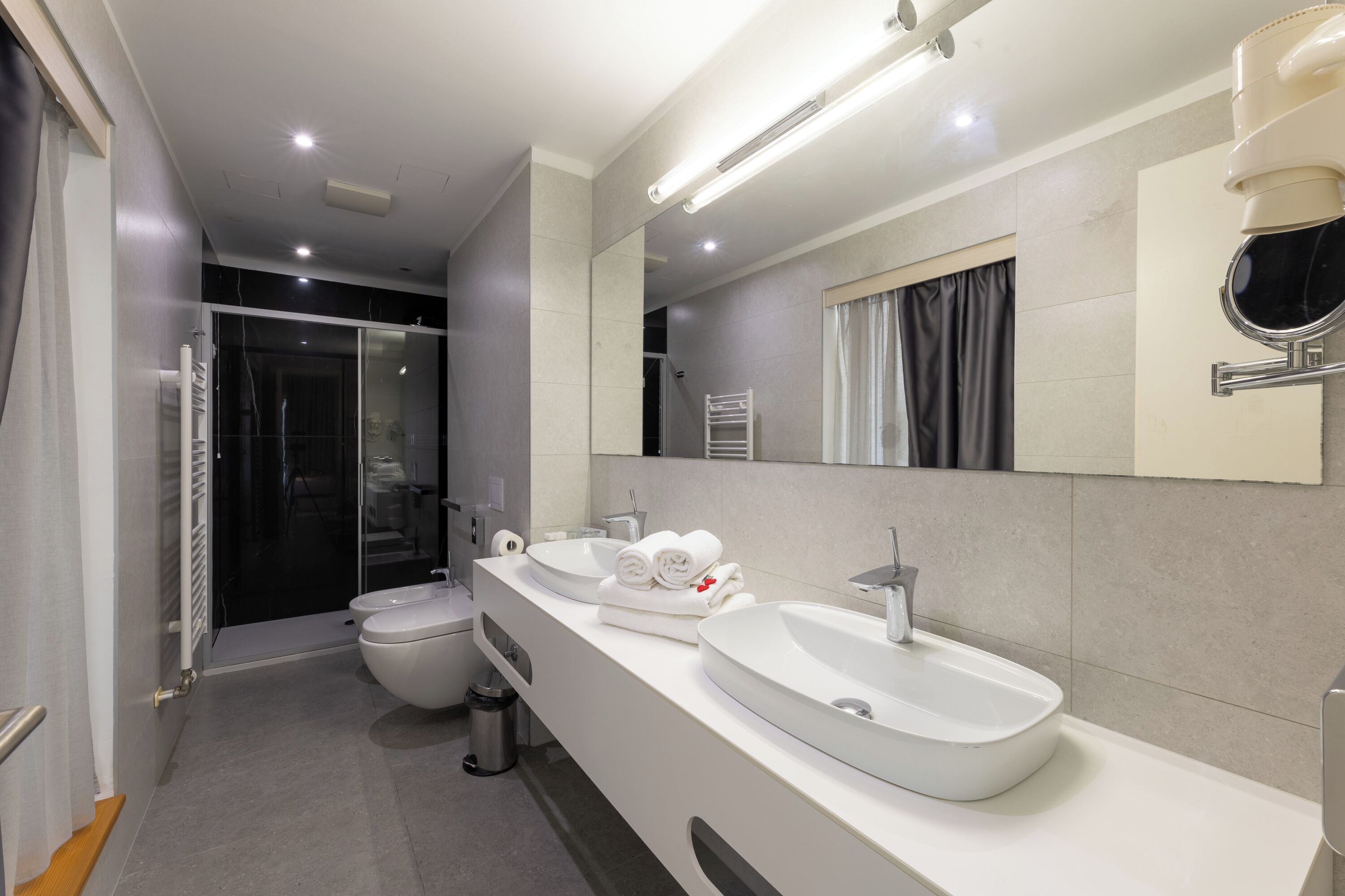 Un baño moderno con dos lavamanos, un inodoro y una ducha.