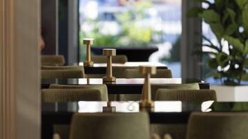 Ein Restaurant mit modernem Interieur, das einen langen Tisch mit Stühlen und einer dekorativen Messingarmatur zeigt.
