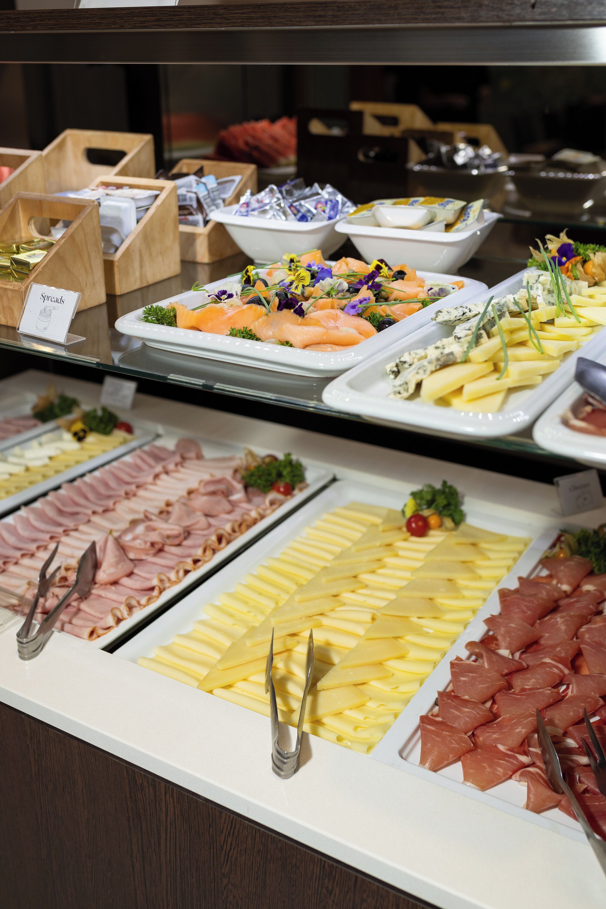 Un bufé con diversas opciones de comida, incluyendo carnes, quesos y mariscos.