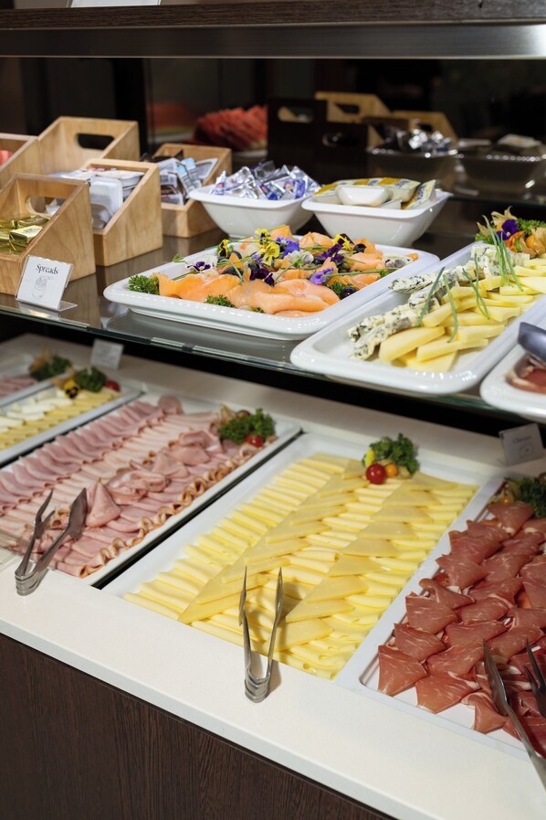 Un bufé con diversas opciones de comida, incluyendo carnes, quesos y mariscos.