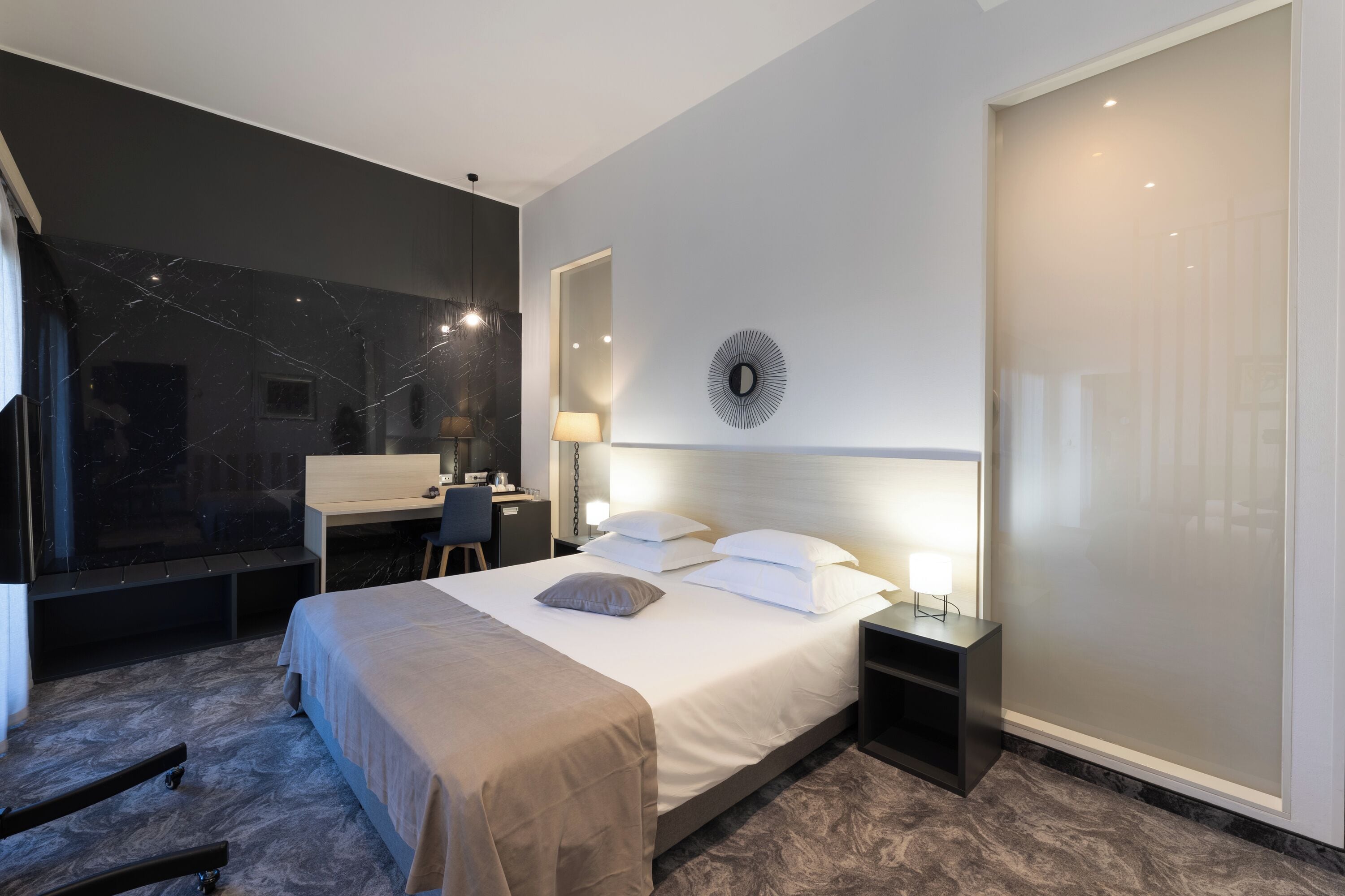 Moderni hotellihuone, jossa on suuri sänky, työpöytä ja tuoli.
