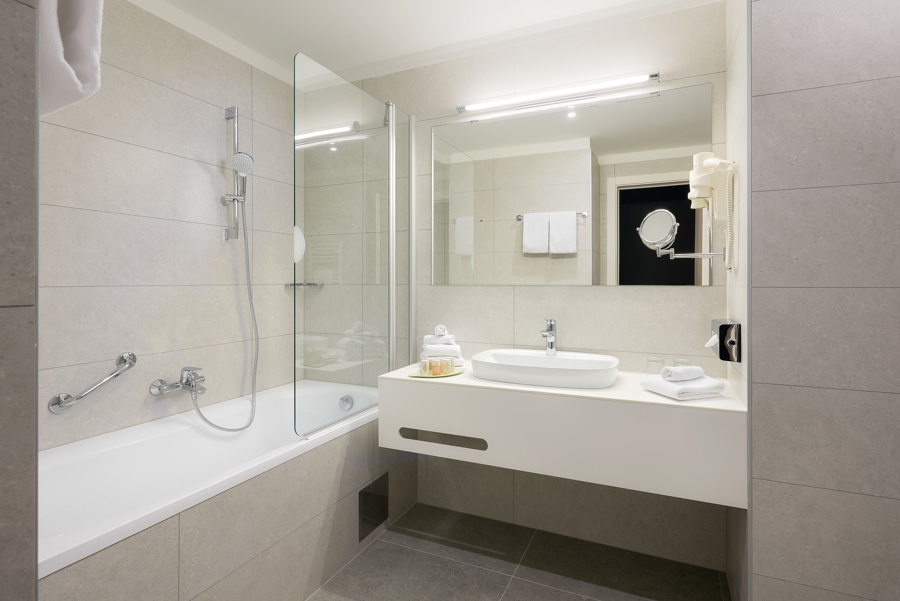 A modern bathroom with a bathtub, a glass-enclosed shower, a sink, and a mirror.