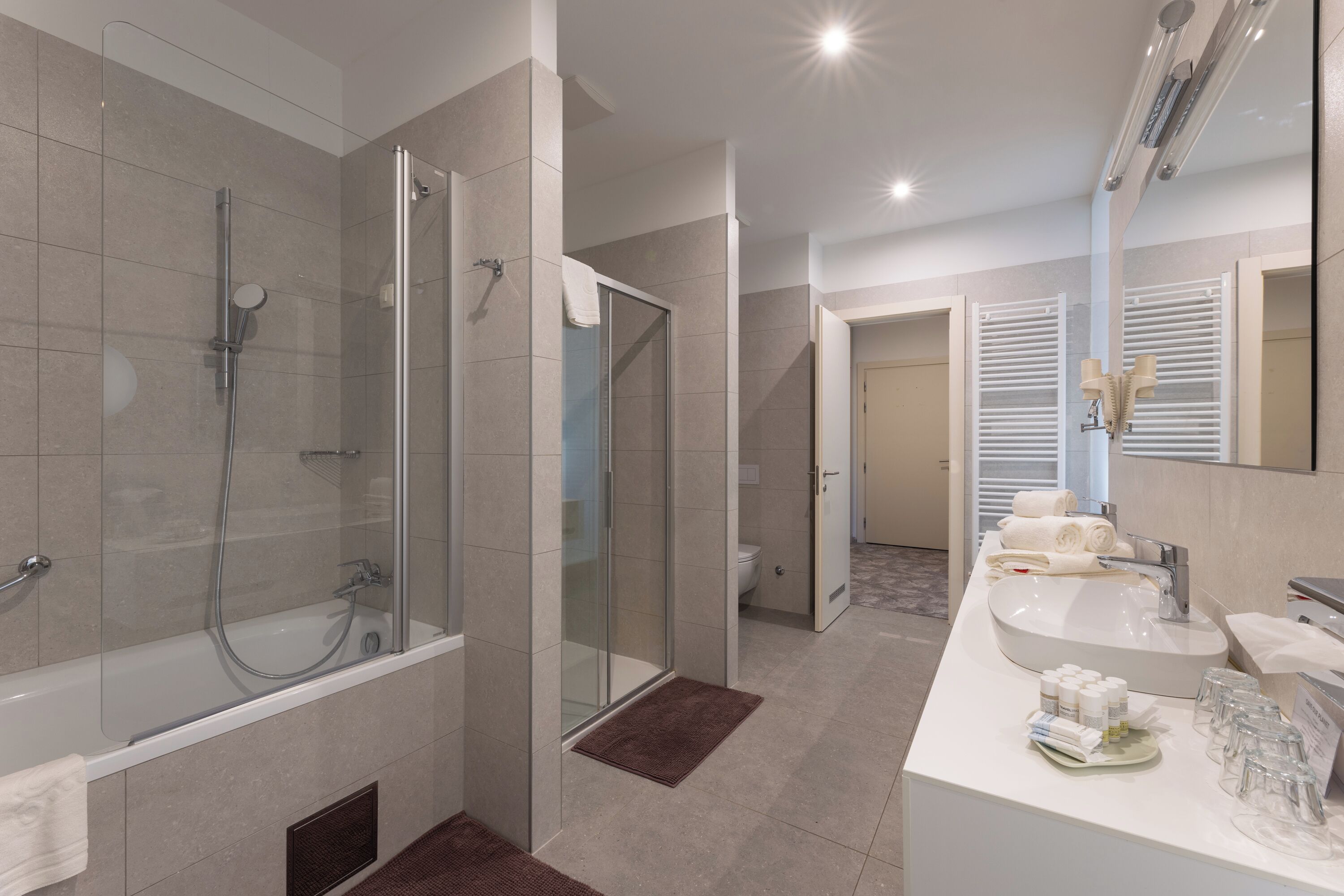 Une salle de bain moderne dotée d’une douche à parois de verre, d’une baignoire sur pieds et d’un meuble-lavabo avec un évier et un miroir.