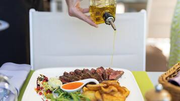Un plat de carn tallada amb salsa i patates fregides.