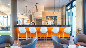 A modern bar area with a counter, orange seating, and hanging pendant lights.