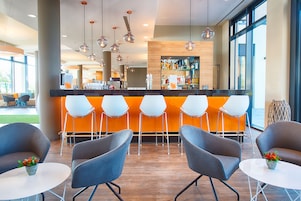 Un área de bar moderna con mostrador, asientos color naranja y lámparas colgantes.
