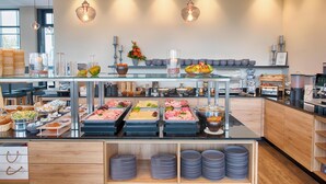 A buffet setup with various food items, a vase with flowers, and hanging pendant lights.
