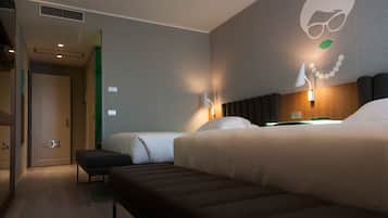 A hotel room with two beds, a bench, a wall-mounted lamp, and a door with a number.