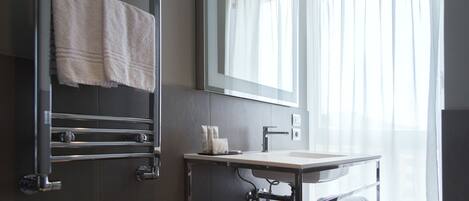 A modern bathroom with a glass shower enclosure, a vanity with a sink, and a towel rack.