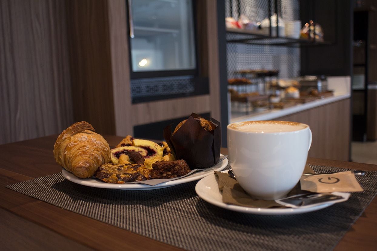 A breakfast setting with croissants, pastries, and a cup of coffee on a table.