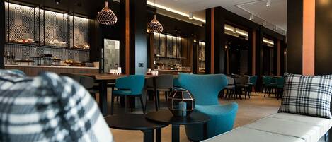 Un moderno vestíbulo de hotel con un área de descanso, un bar y una recepción.