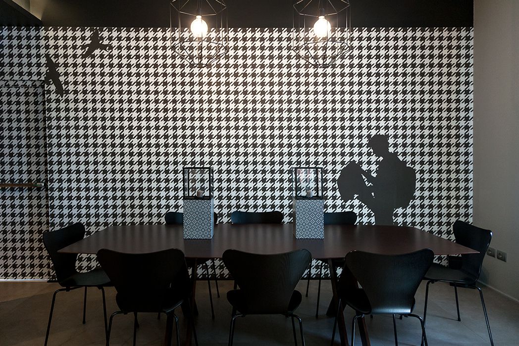 A conference room with a houndstooth patterned wall, a round table, and six chairs.