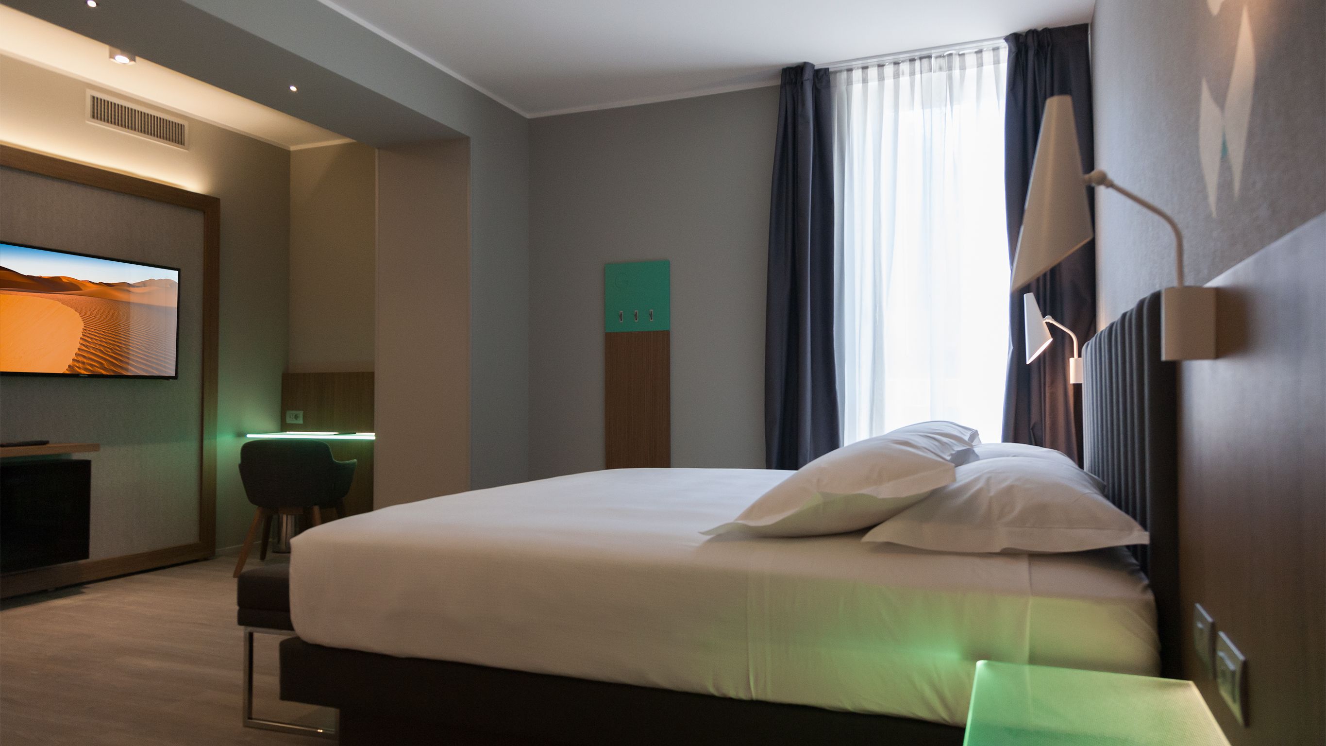 Habitación de hotel con una cama grande, un escritorio, un televisor de pantalla plana y vistas al desierto por la ventana.