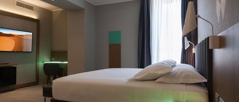 Habitación de hotel con una cama grande, un escritorio, un televisor de pantalla plana y vistas al desierto por la ventana.