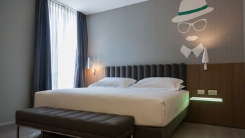 Una habitación de hotel moderna con una cama grande, un banco y una lámpara fijada a la pared.