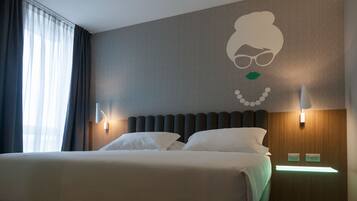 Habitación de hotel con una cama grande, dos lámparas de noche, una luz en la pared y una ventana con cortinas.