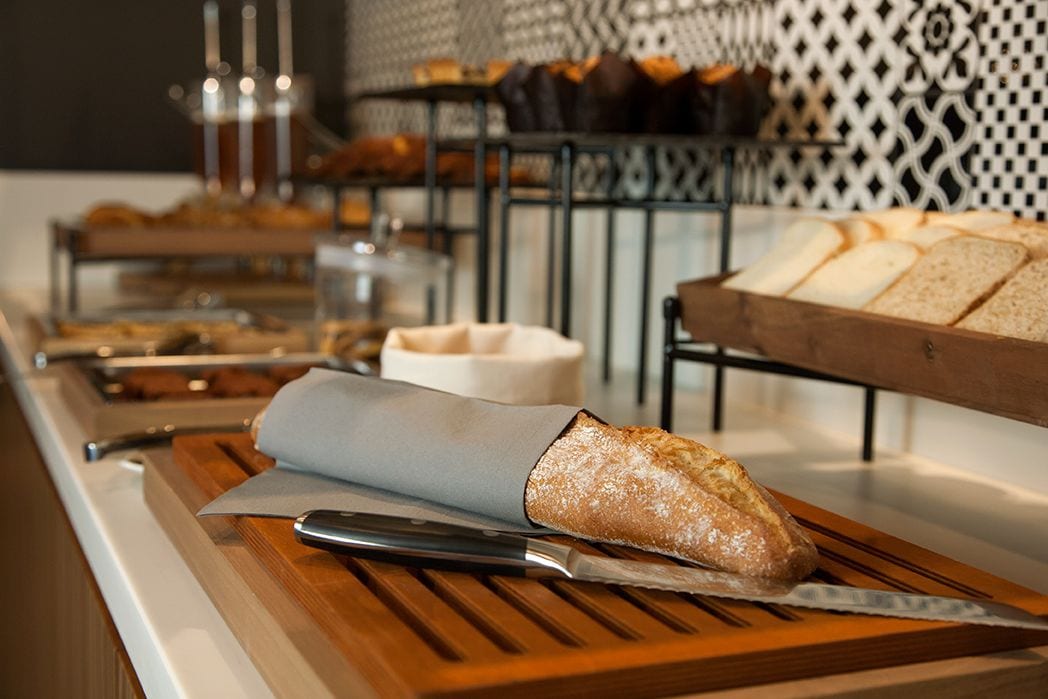A buffet setup with various food items, including bread and pastries, on wooden serving boards.