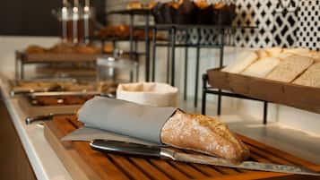 Un buffet proposant une variété de plats, notamment du pain et des viennoiseries, présentés sur des plateaux de service en bois.