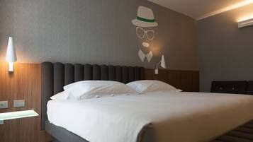 Una cama bien tendida con sábanas blancas, cabecera con ranuras verticales y una lámpara de pared.
