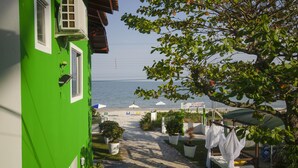 Un edificio verde con vista al mar, mobiliario exterior y plantas en macetas.