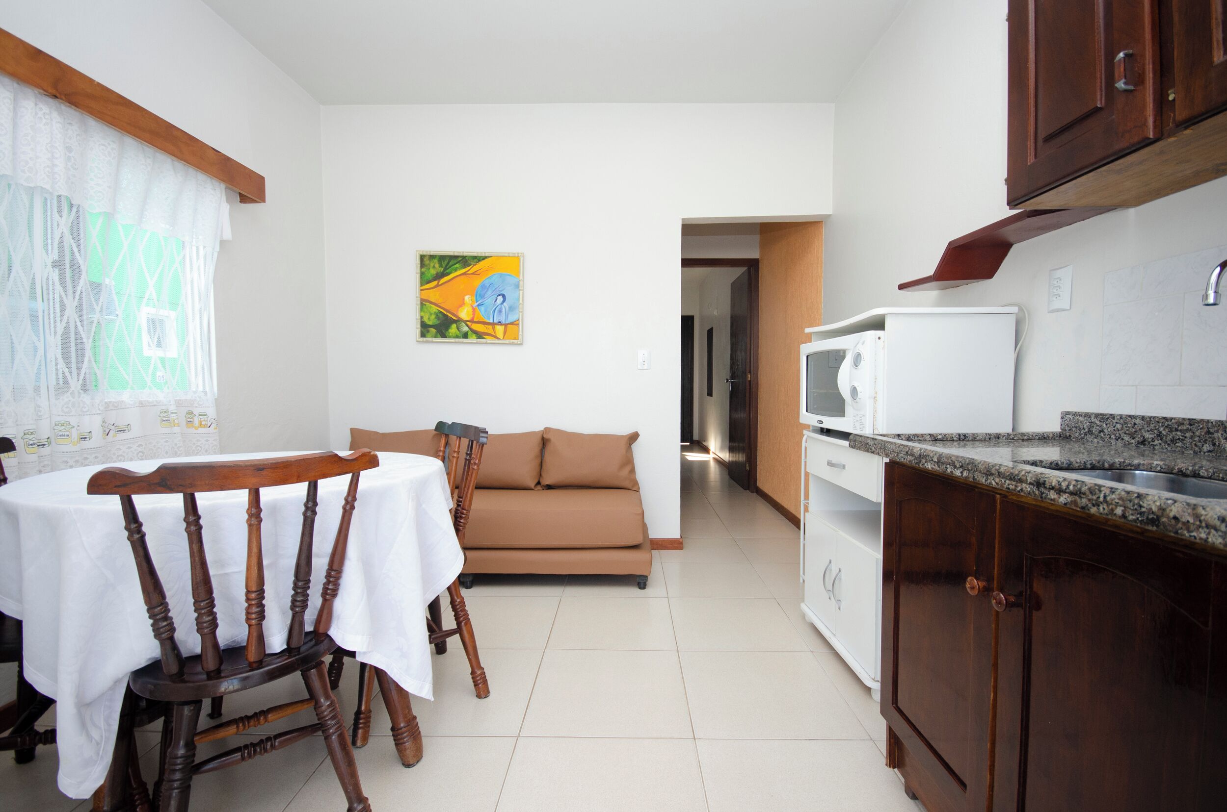 A compact kitchen with a dining table, a sofa, and a microwave.