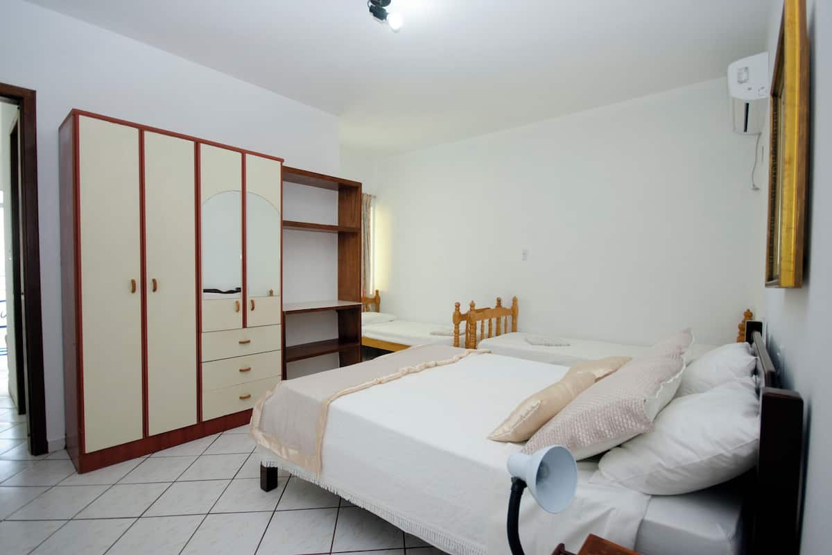 A bedroom with two single beds, a wardrobe, a mirror, and a ceiling light.